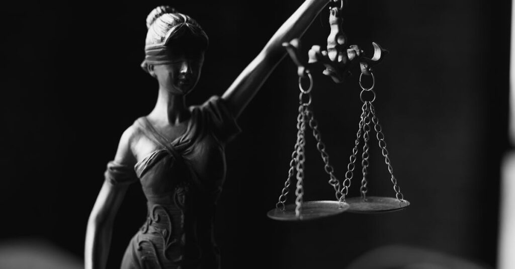 A close-up black and white photo of the Lady Justice figurine with scales.