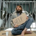 Is Begging Legal in India? A Compassionate Look at the Laws and Realities A homeless man sits under a bridge with a sign reading 'HELP', highlighting poverty and homelessness.