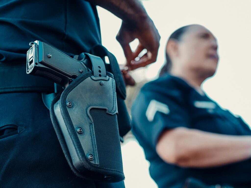 Police officers with a focus on a holstered handgun, demonstrating law enforcement readiness.