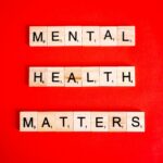 Wooden tiles spelling 'Mental Health Matters' on a vivid red background.