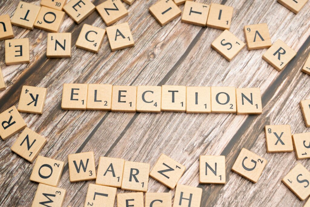 Wooden letter tiles form the word 'election' on a textured wooden surface, symbolizing voting.