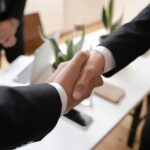 Close-up of a handshake between two professionals in a business setting, symbolizing agreement.