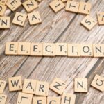 Wooden letter tiles form the word 'election' on a textured wooden surface, symbolizing voting.