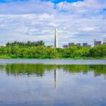 A modern cable-stayed bridge spans over a tranquil lake with lush green surroundings.