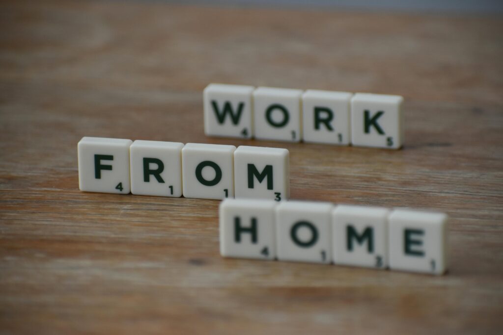 Close-up of Scrabble tiles on wooden table spelling 'Work From Home' concept.