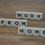 Close-up of Scrabble tiles on wooden table spelling 'Work From Home' concept.