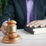 A wooden gavel and legal book represent justice in a court setting, emphasizing order and legal authority.