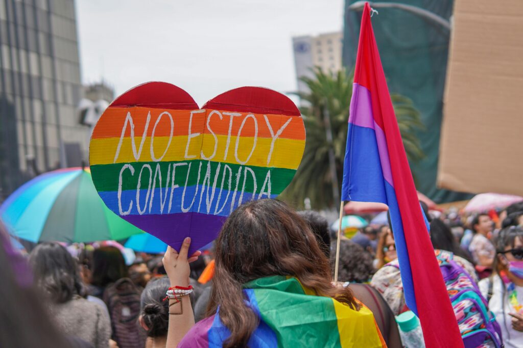 Vibrant LGBT pride gathering in Mexico City featuring rainbow flags and a heart-shaped placard.