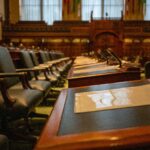 A detailed view of an empty legislative chamber with rows of desks and microphones, evoking governance.